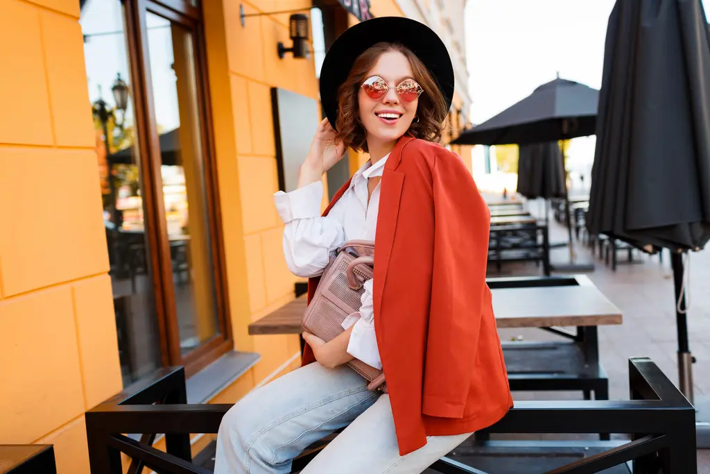 Femme à la mode portant un chapeau, des lunettes, une veste rouge