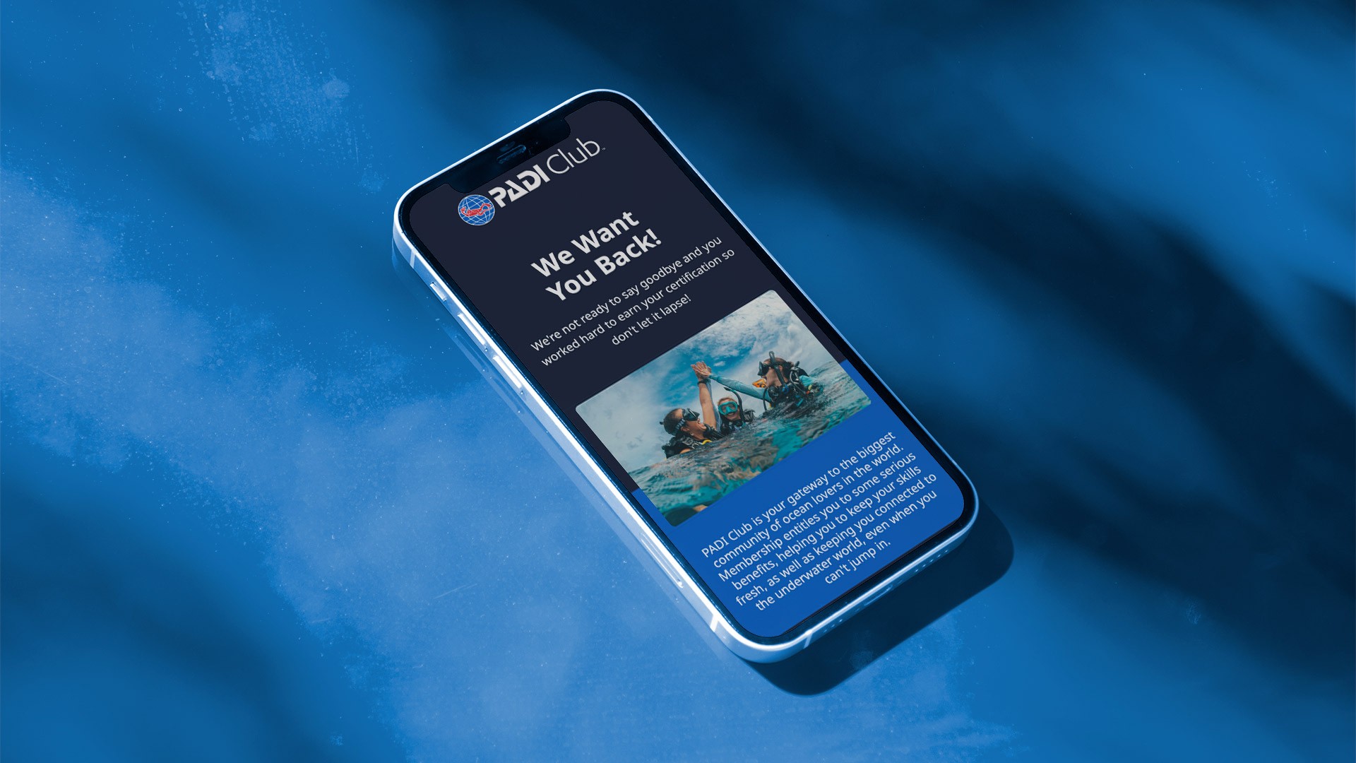 Angled smartphone mockup displaying a PADI Club re-engagement email campaign featuring underwater lifestyle imagery, membership messaging, and mobile-first email design within PADI’s branded communication system.