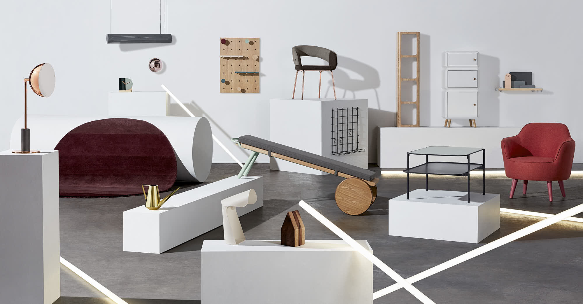 A contemporary arrangement of various geometric shapes and objects in neutral tones with pops of red and graphic elements.