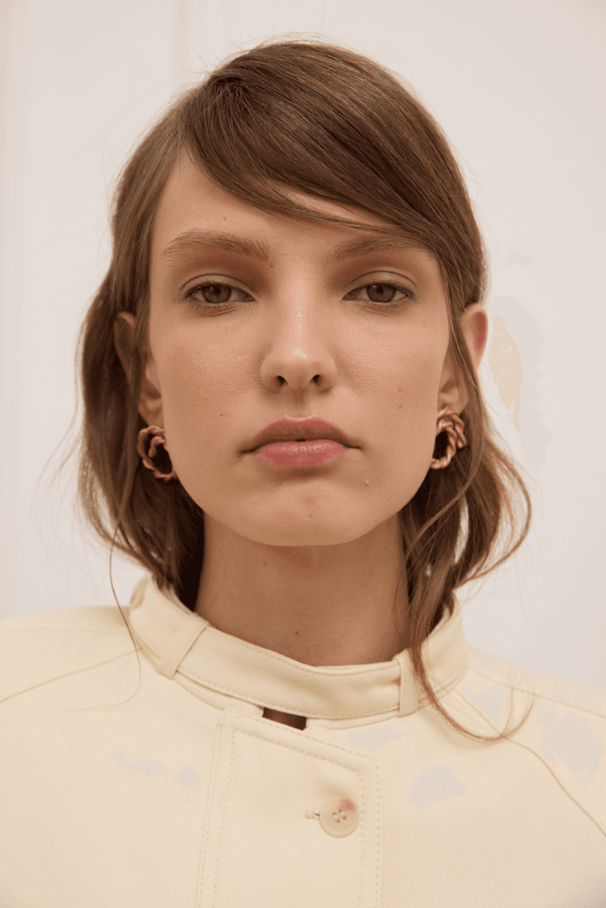 Woman wearing gold hoop earrings against a plain background