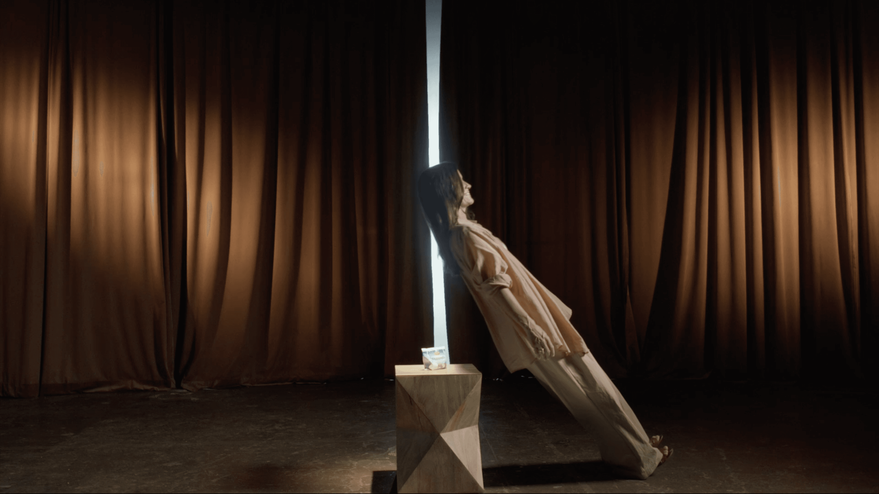 A woman smiling as she falls backwards in a trust fall onto a large LIDL product, captured in a bright, modern summer commercial spot.