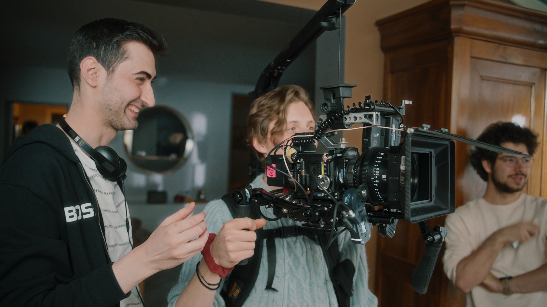 Deux membres de l'équipe de tournage ajustant une caméra professionnelle sur un plateau en intérieur.