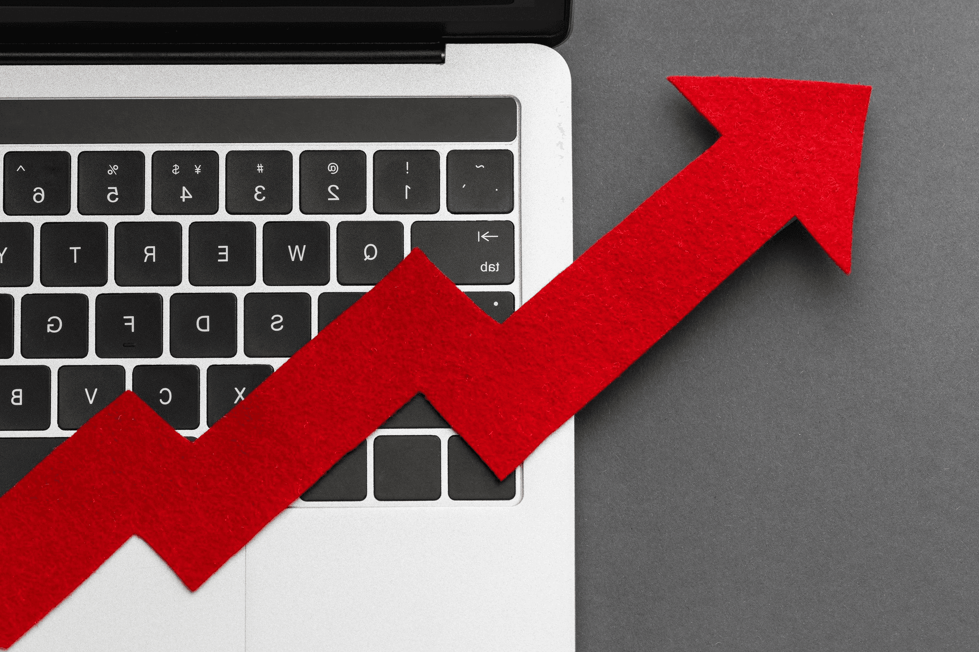 Top-down view of a red arrow pointing upward across a laptop keyboard.