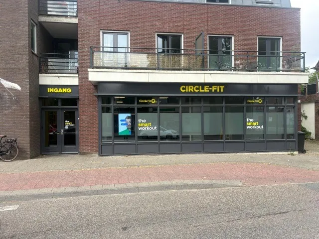 A modern Circle Fit building with large yellow windows, set against a clear blue sky.