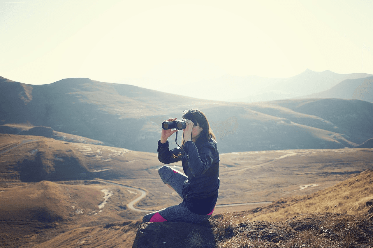 Woman on a hill with binoculars.