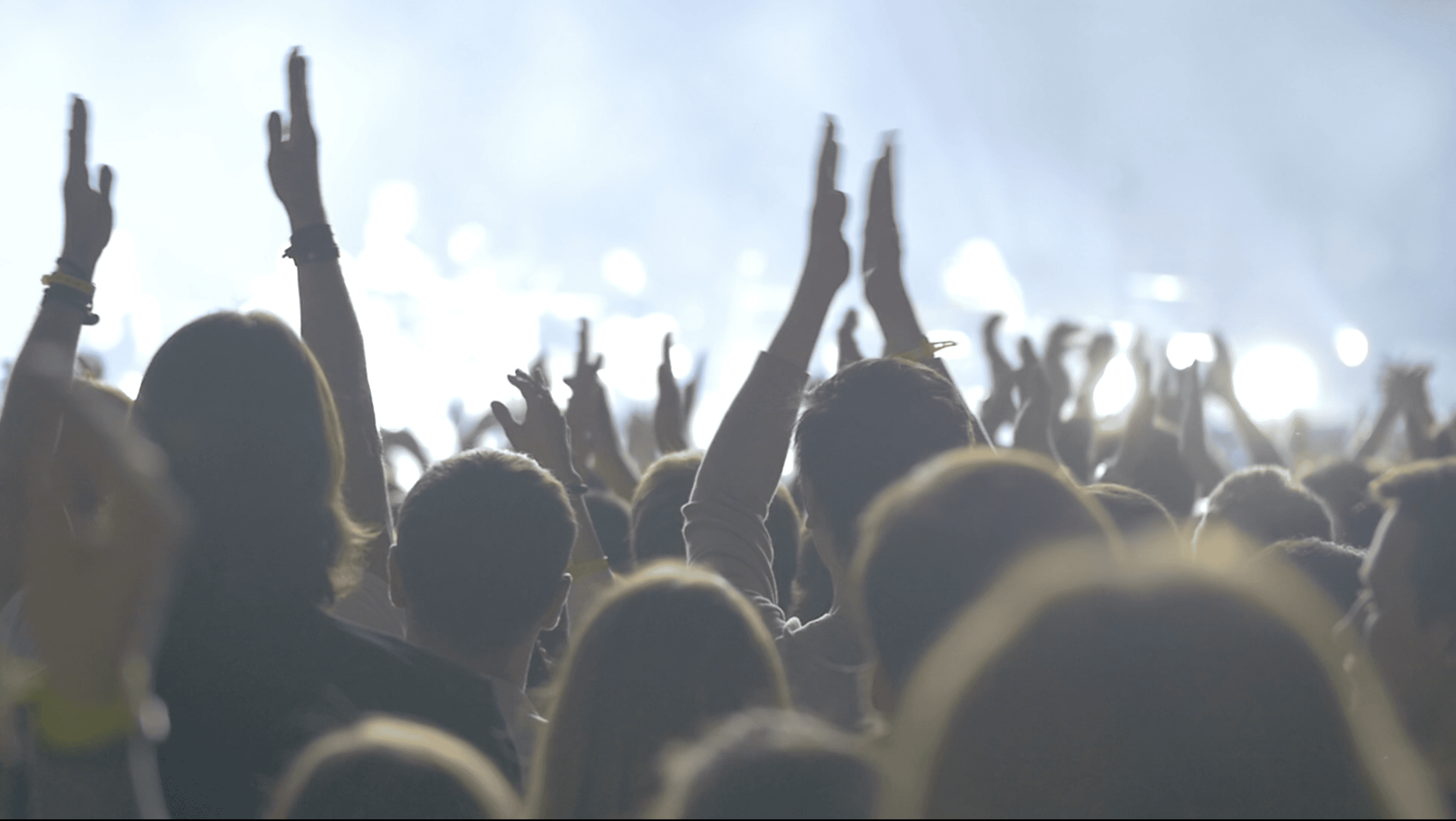 Live music audience with hands raised at a Playhuman creator event — stage lighting and haze in the background