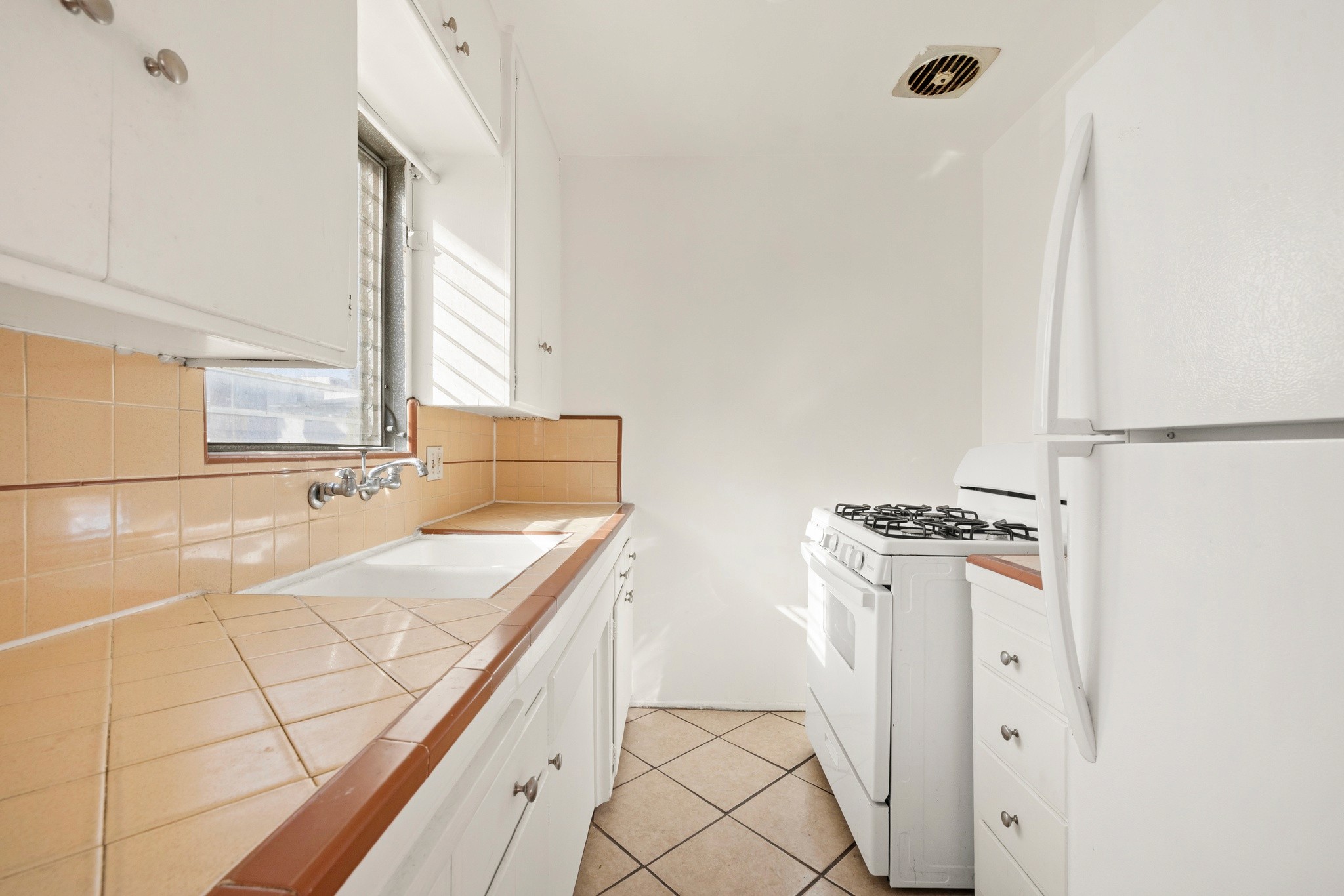 Compact kitchen with tile counters, cabinetry, and appliances at 436 Normandie Pl.