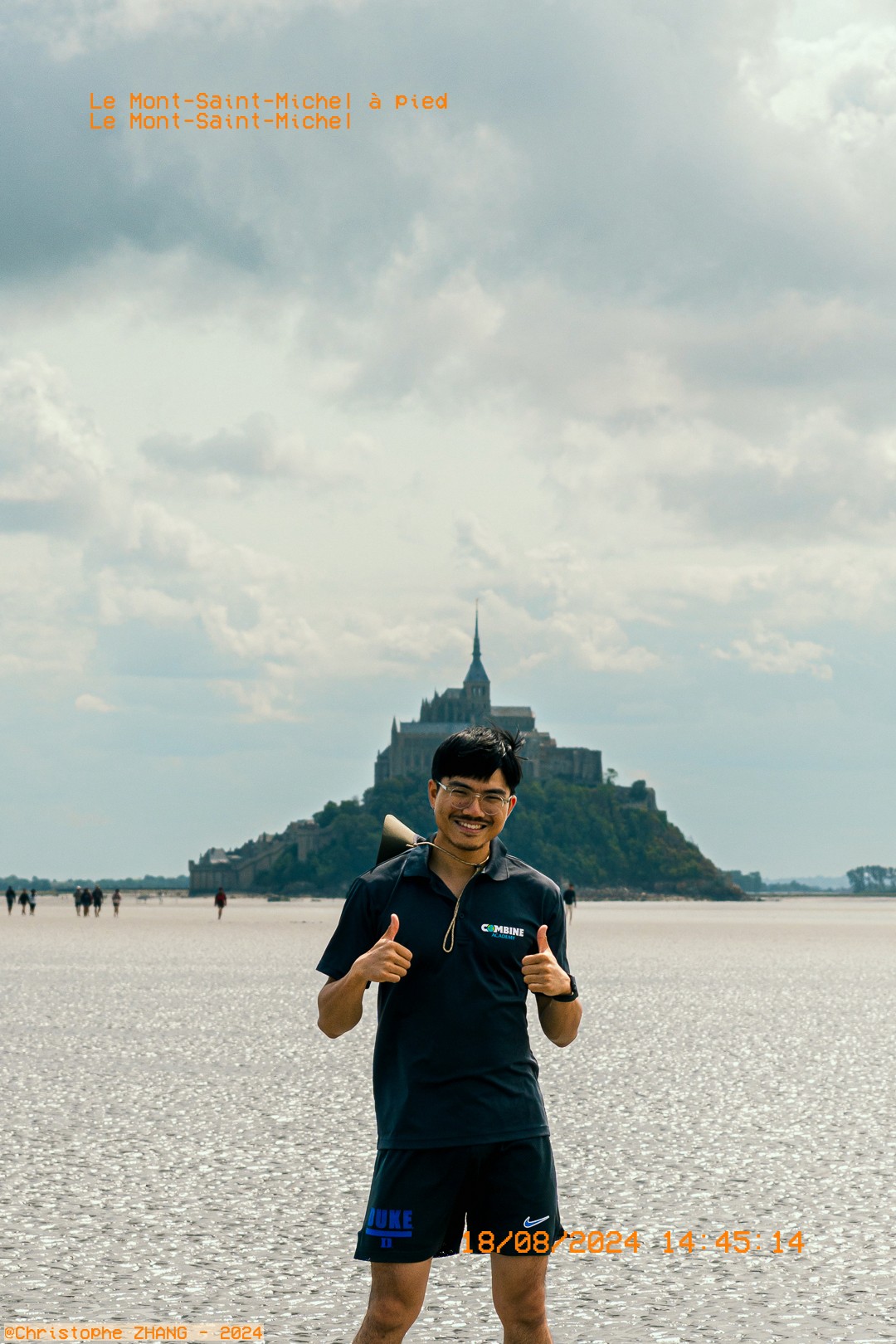 Jeune homme souriant, se tenant devant le Mont Saint-Michel.
