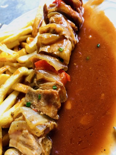 Close-up of a dark green leaf showing its textured surface and central vein against a muted background.