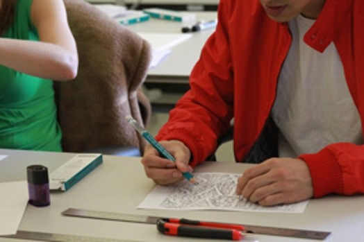 A photo of two people, each drawing a sketch on a piece of paper.