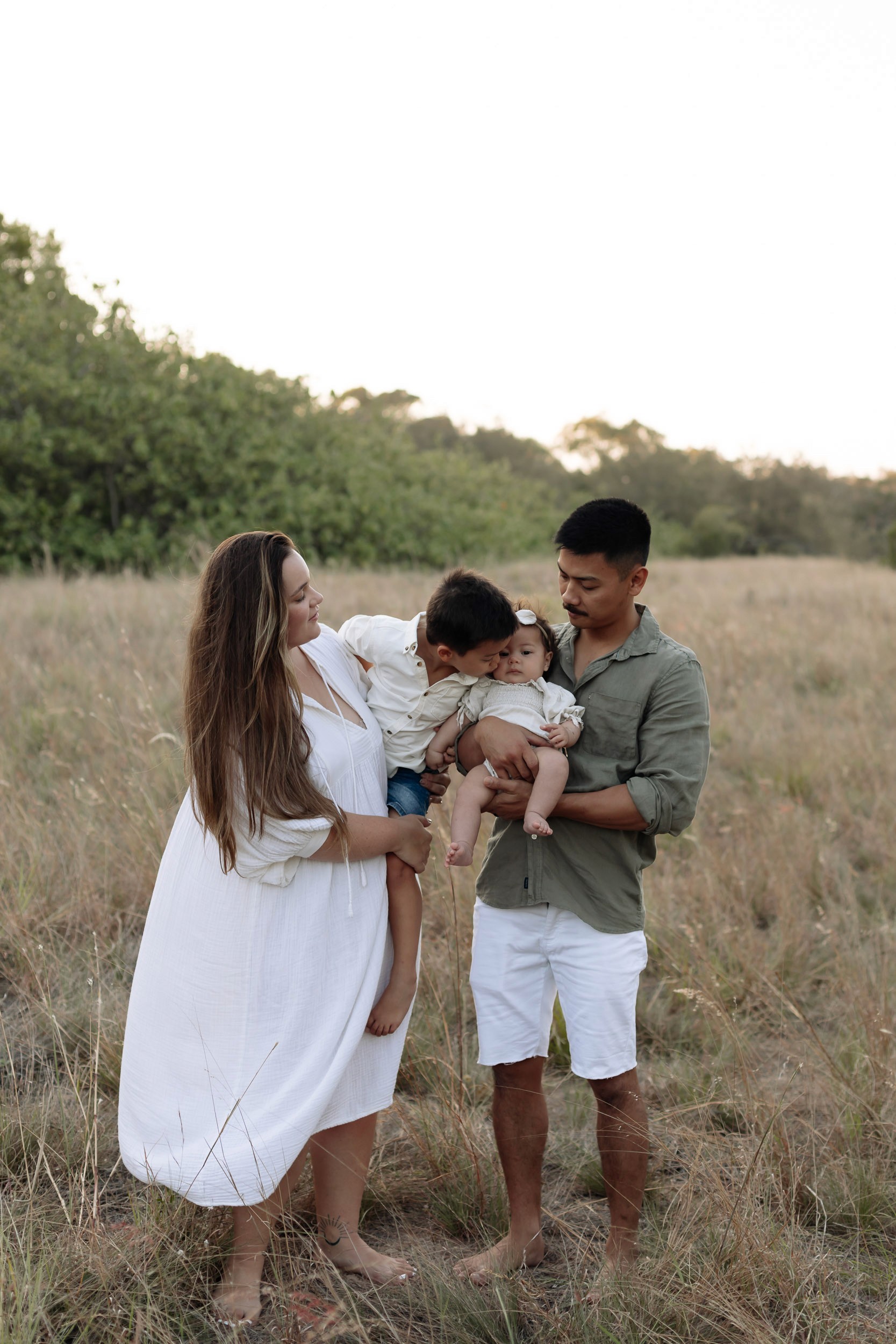 Mackay family photography session at sunset in a grassy field with parents, baby girl and young boy
