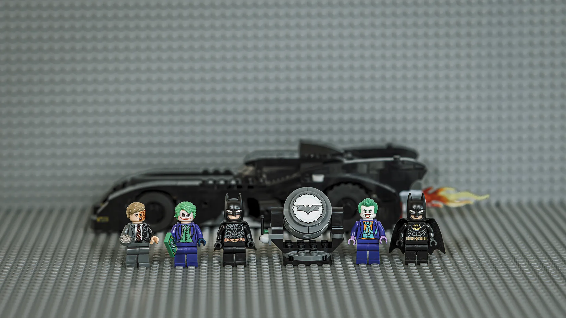 Kjente karakterer, batsignal og batmobile i bakgrunn