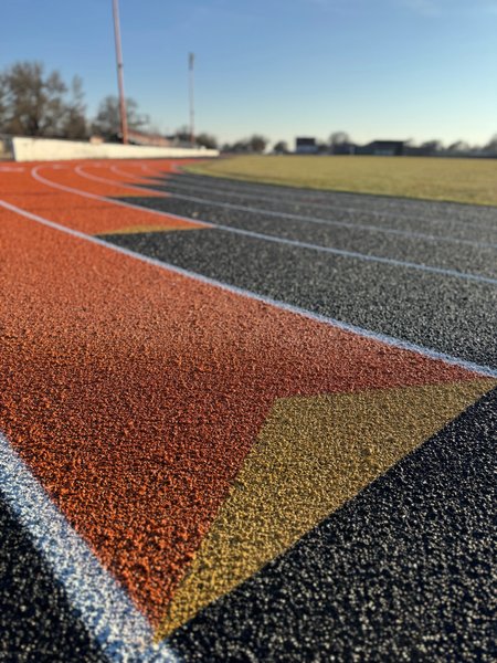 Close up of orange and black track lanes with a yellow triangle marking