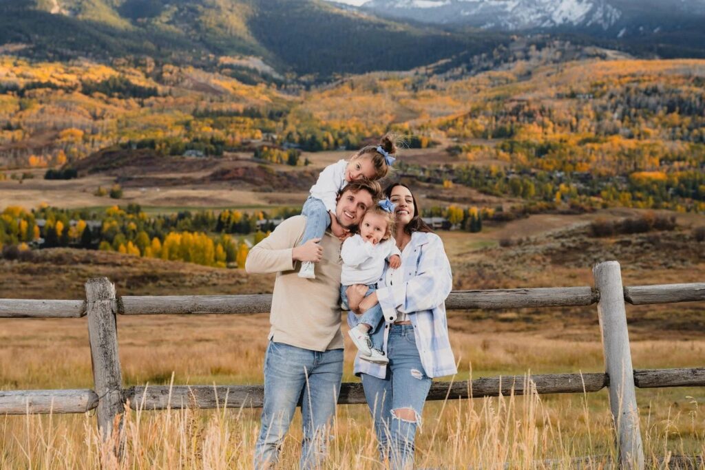 Family of four embracing at a mountain overlook in autumn