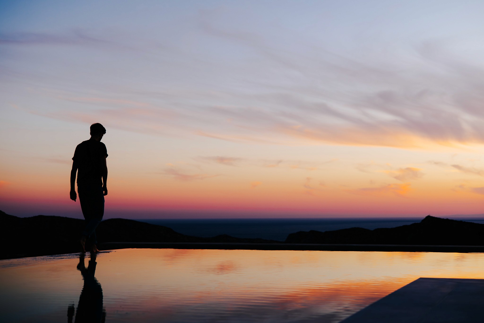 Silhouette eines Mannes vor dem Infinity-Pool bei Sonnenuntergang – Magischer Moment in der Luxusvilla Lala House Kreta