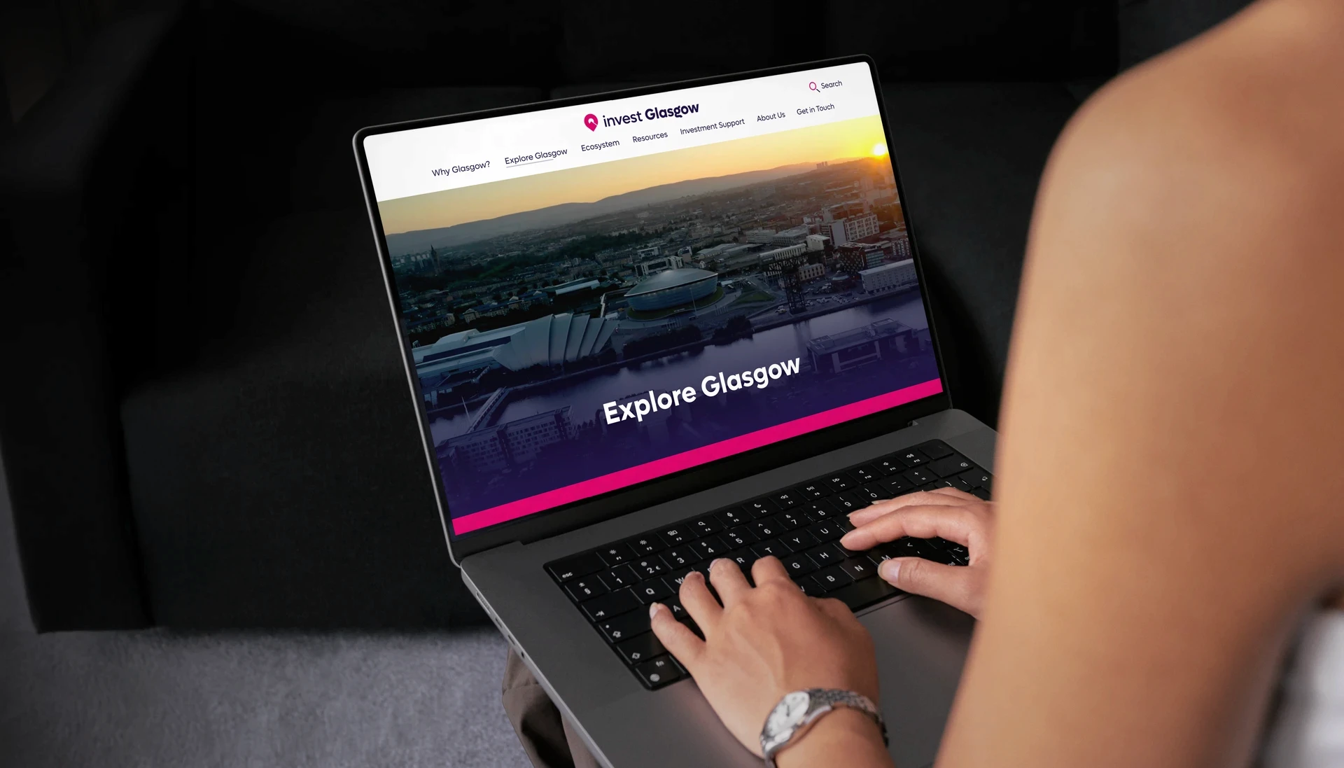 Woman holding laptop viewing the Explore Glasgow section of the Invest Glasgow website