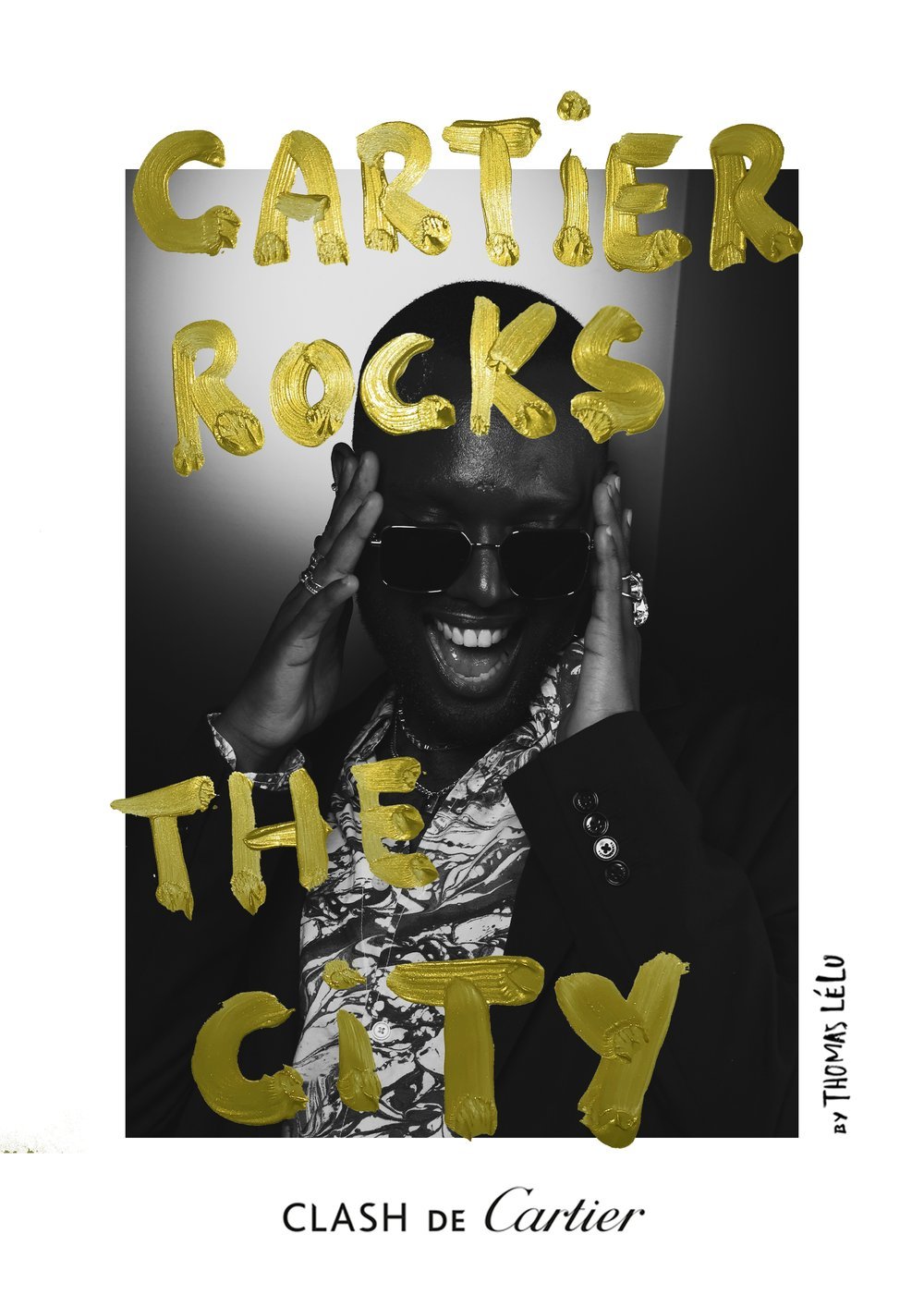 Black and white photo of a smiling person wearing sunglasses, holding their head with both hands, with yellow letters spelling out "GARTIER ROCKS THE CITY" over their face and upper body, and text "CLASH DE Cartier" at the bottom.