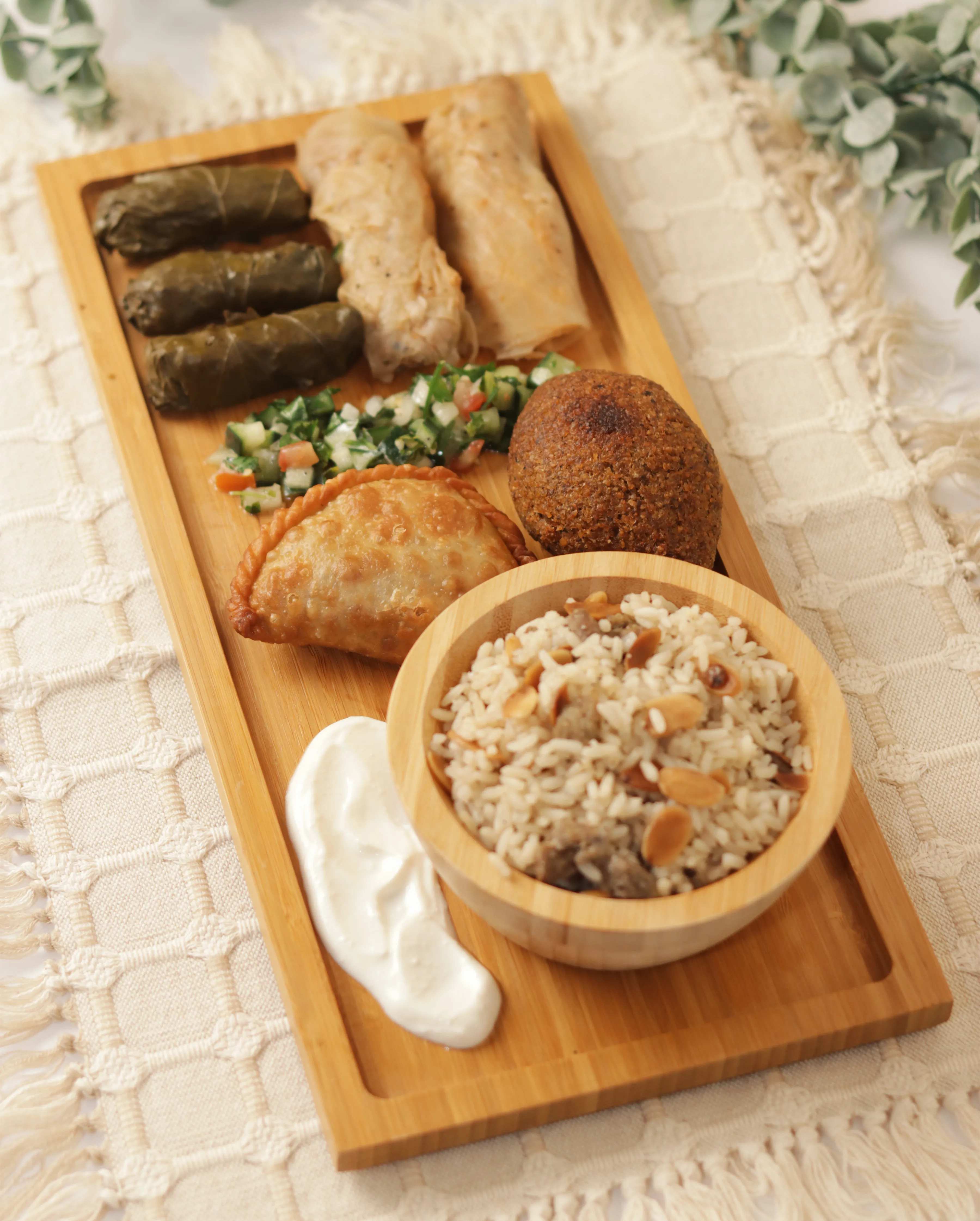 Tabla de madera con platillos libaneses y crema blanca.