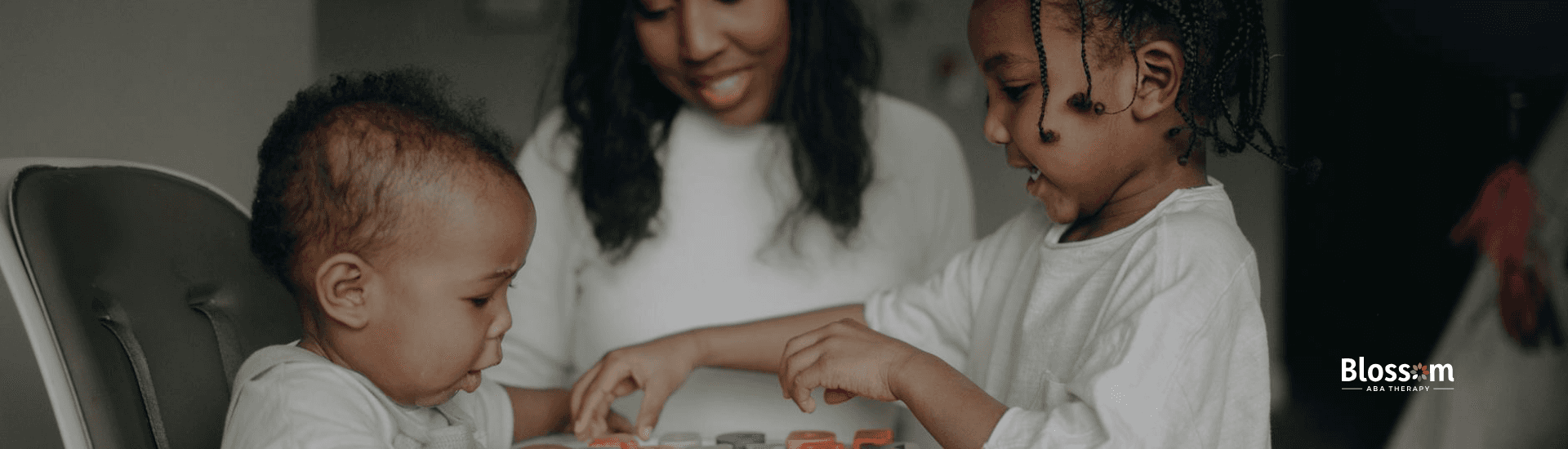 Two young children with autism playing with a wooden puzzle while a smiling BCBA looks in Georgia.