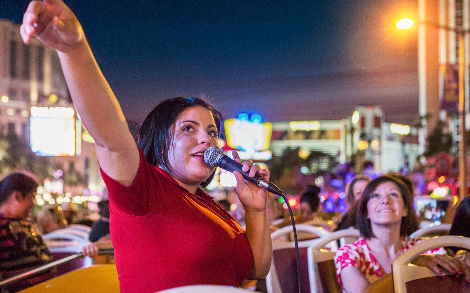 Tour guide speaking on a microphone during a panoramic night tour in a city.