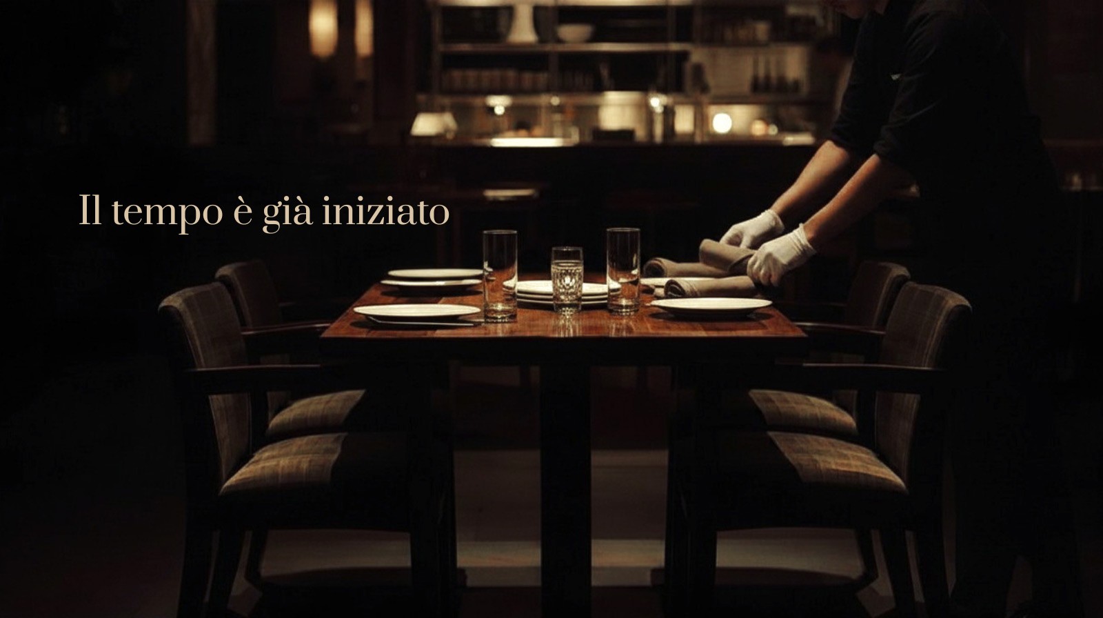 Tavolo di ristorante in fase di preparazione con chef sullo sfondo – esperienza gastronomica lenta e curata