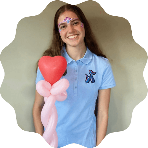 Amelia smiling and posing with a heart wand and flower face paint
