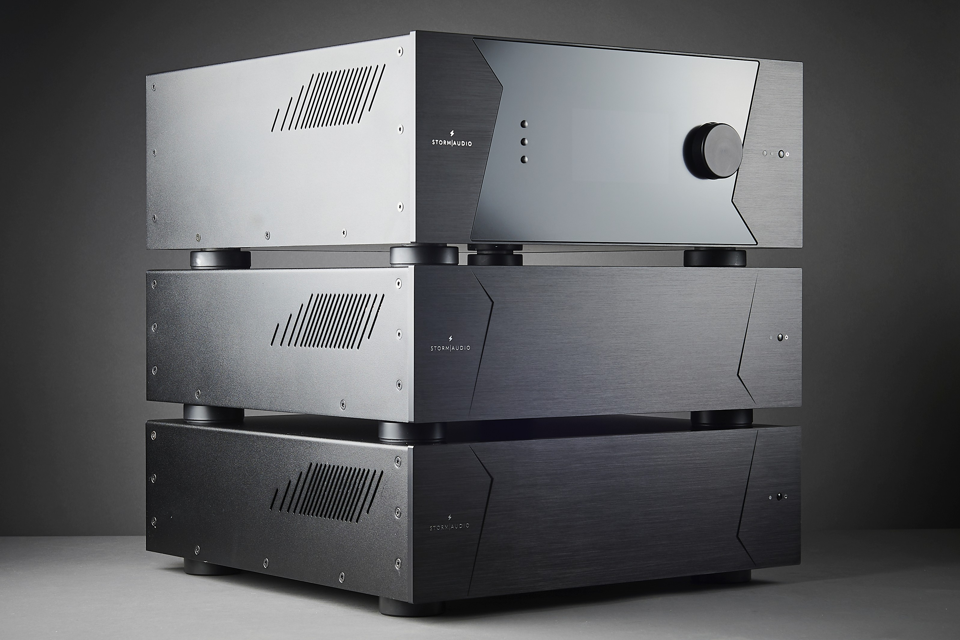 Three stacked StormAudio amplifiers on a dark background.