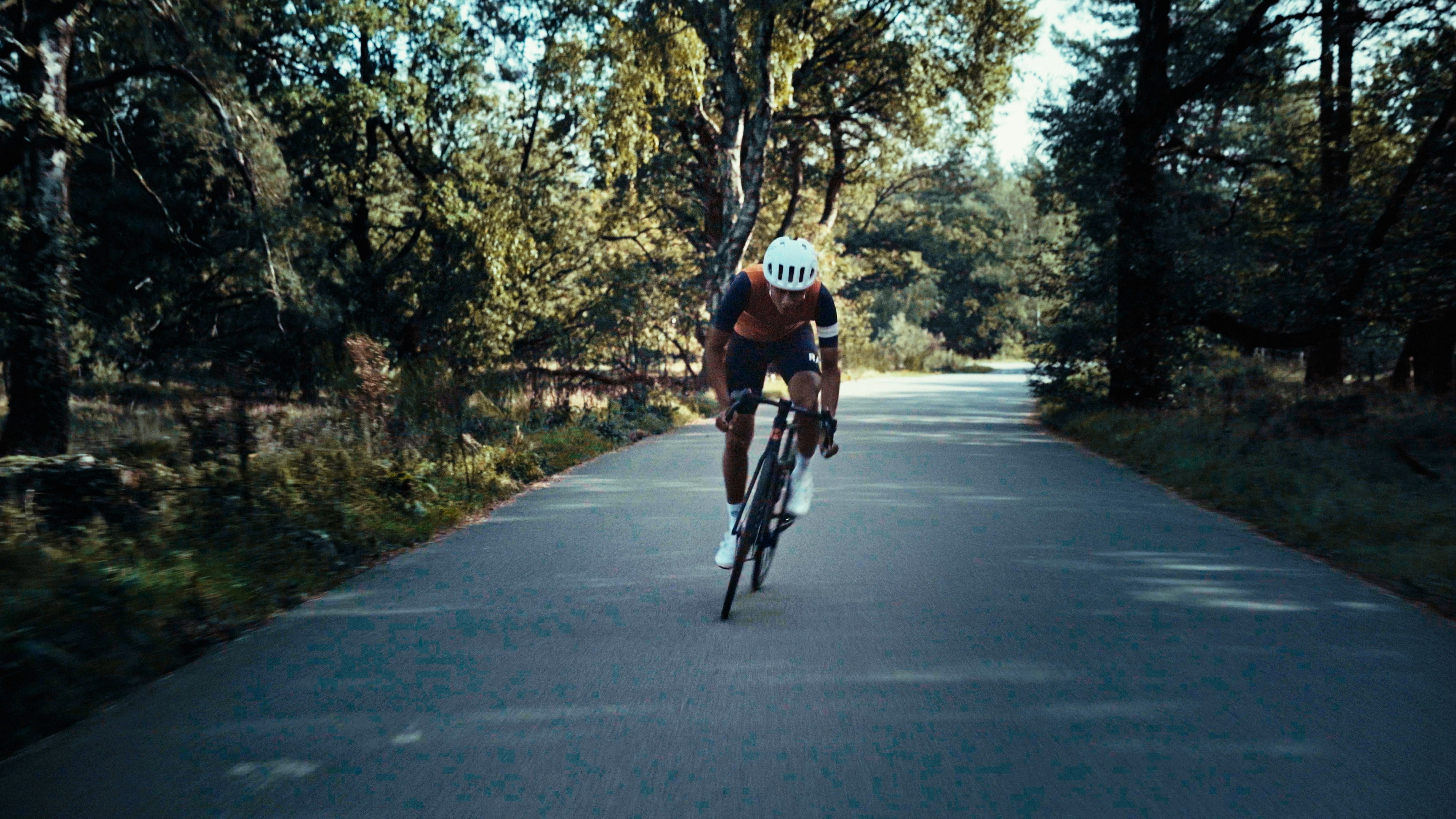 A fast-moving cyclist on a paved path through the forest