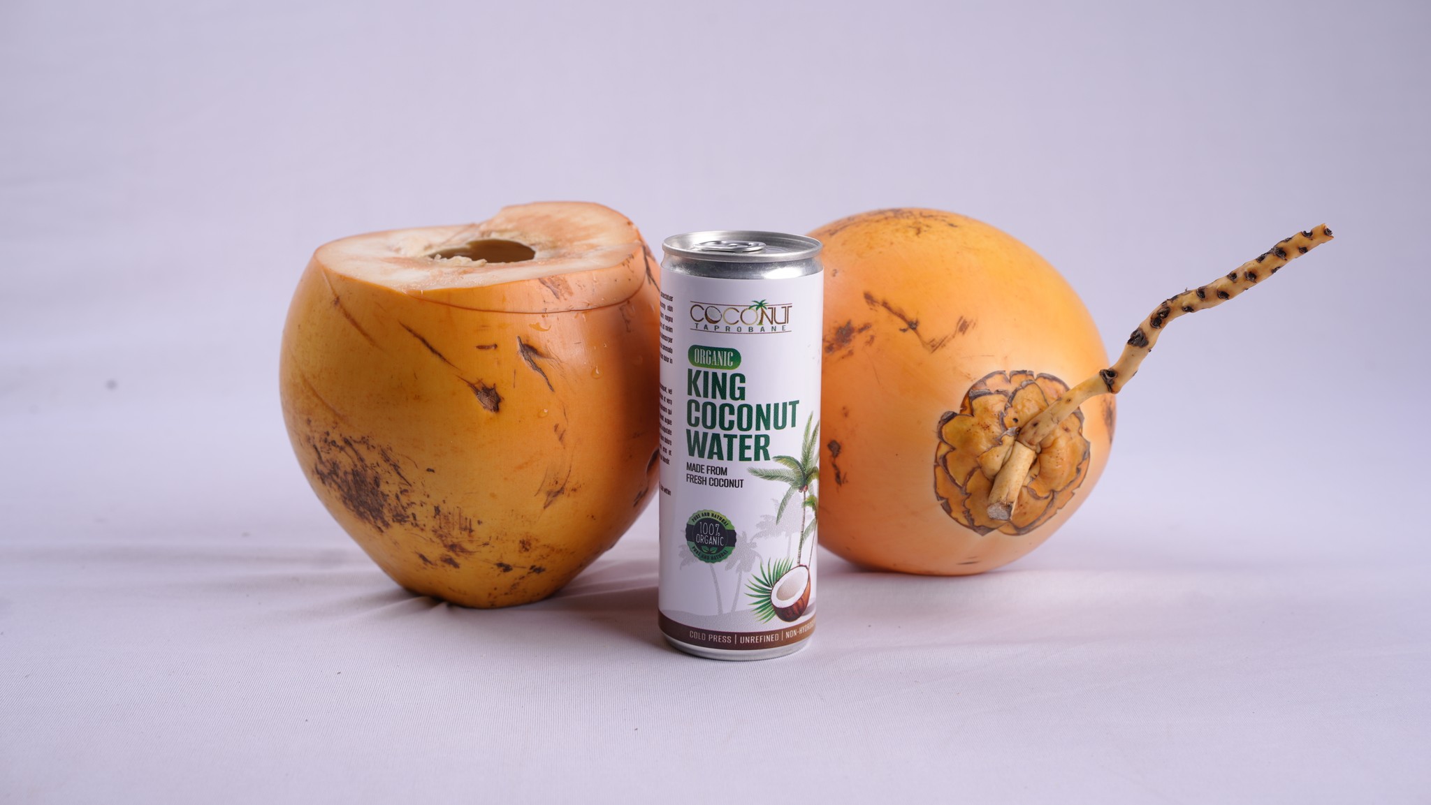 A can of Hulu Natural Organic Coconut Water in front of two king coconuts.