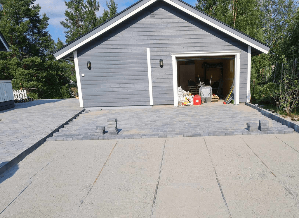 Garasje med steinlagt parkeringsplass.