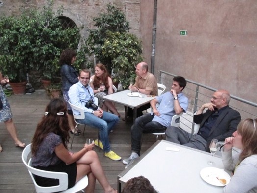 A photo of a group of persons siting at a few restaurant tables while talking.