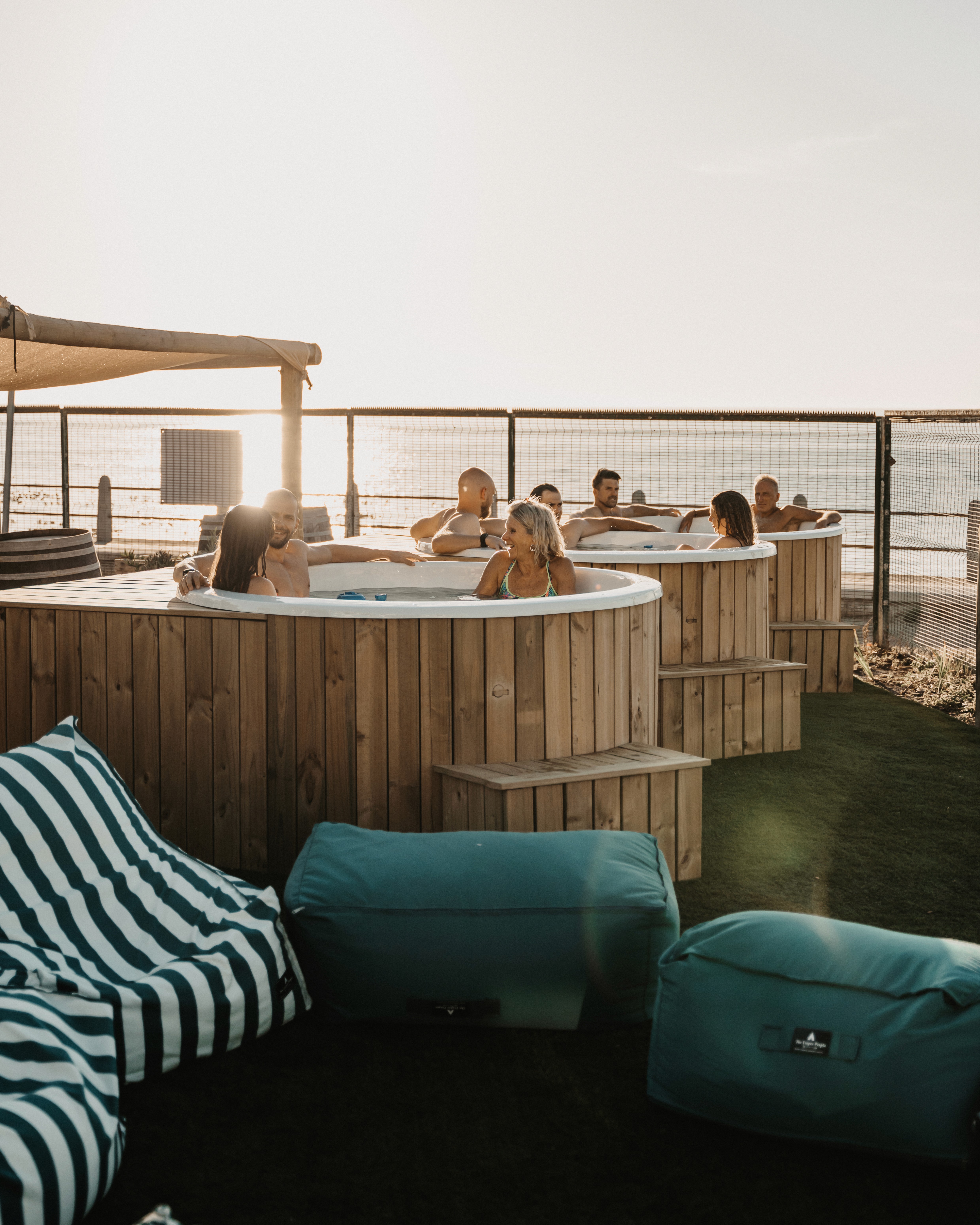 Guests relaxing in the outdoor cold plunge tubs at SaunaHaüs Cape Town at sunset, overlooking the Sea Point Promenade.
