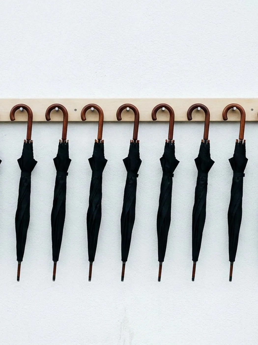 Black umbrellas hanging on a wooden rack