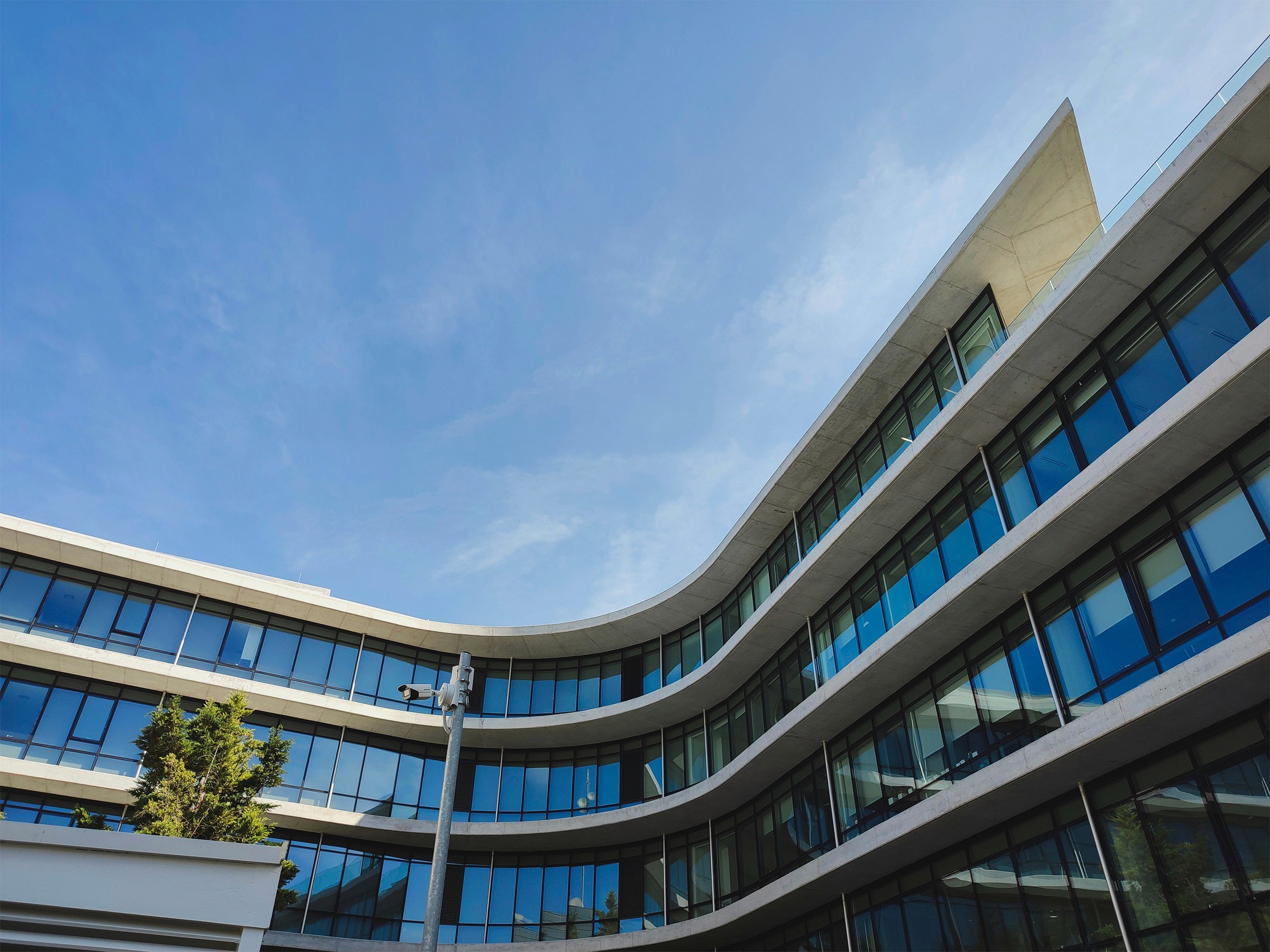 Sleek curved building with expansive glass windows, reflecting the sky and cityscape.
