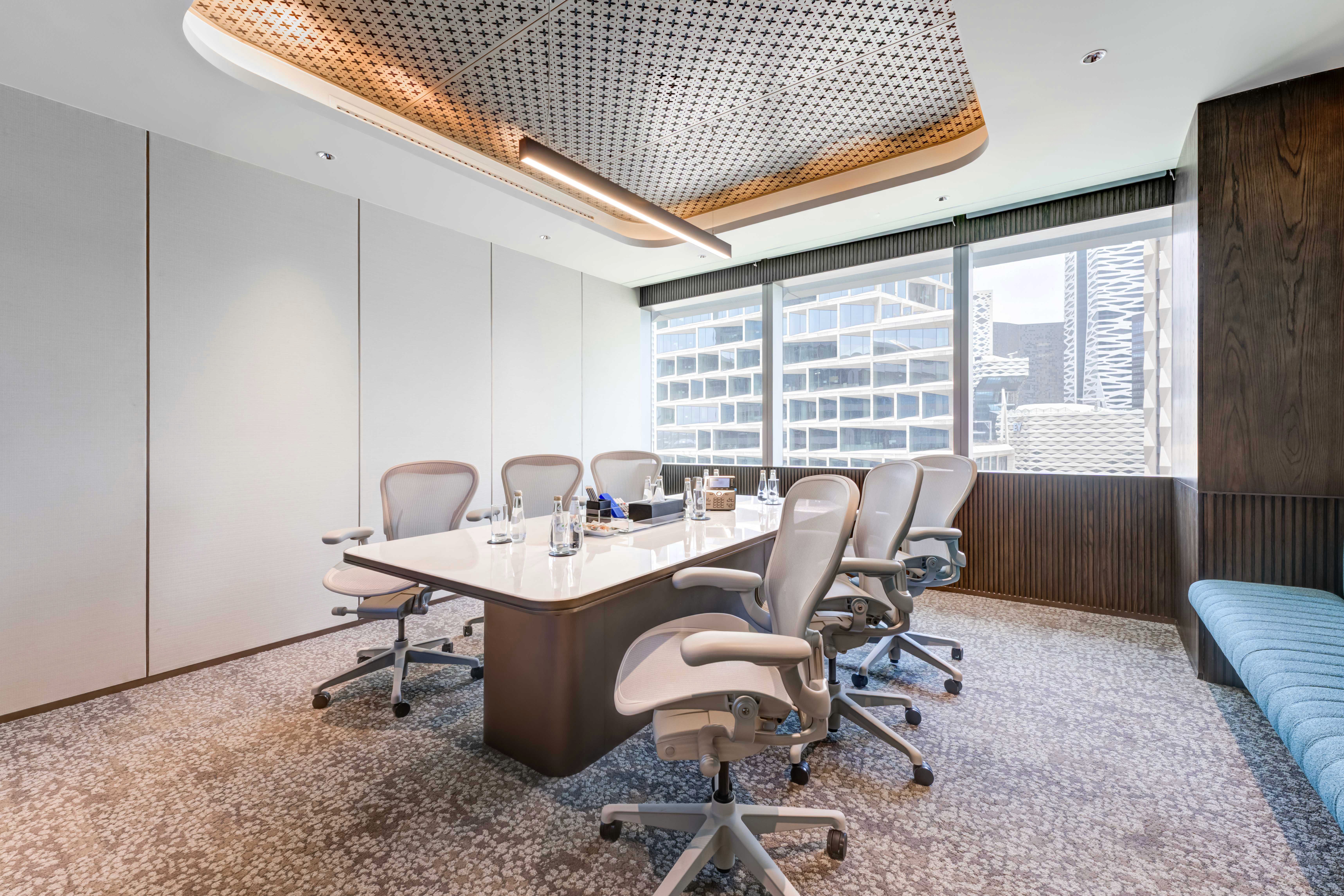 Sleek conference area with a long table, office chairs, and an elegant ceiling design.