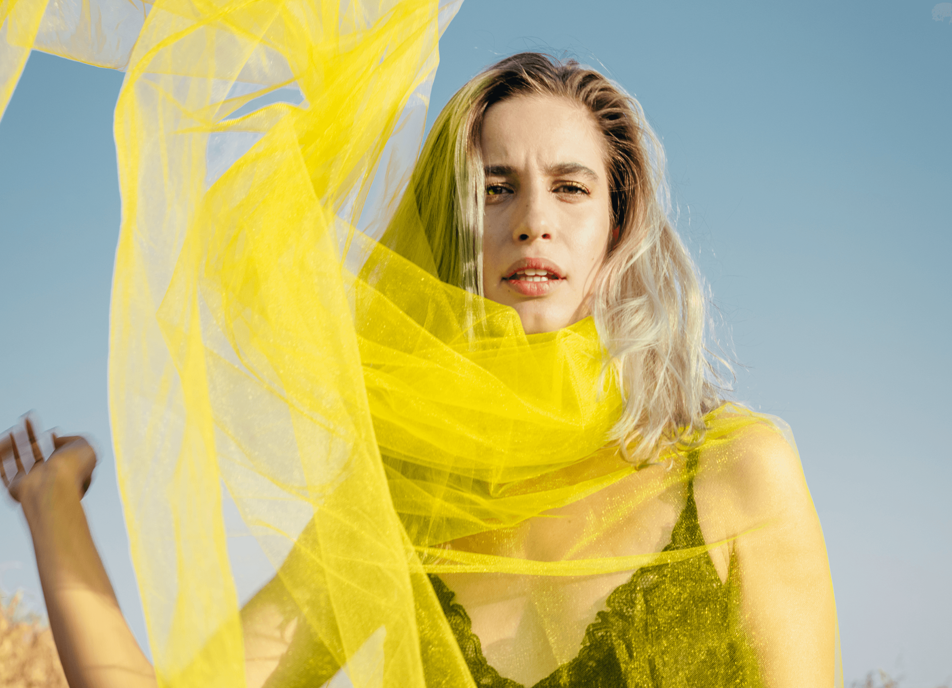 Woman in yellow fabric against blue sky