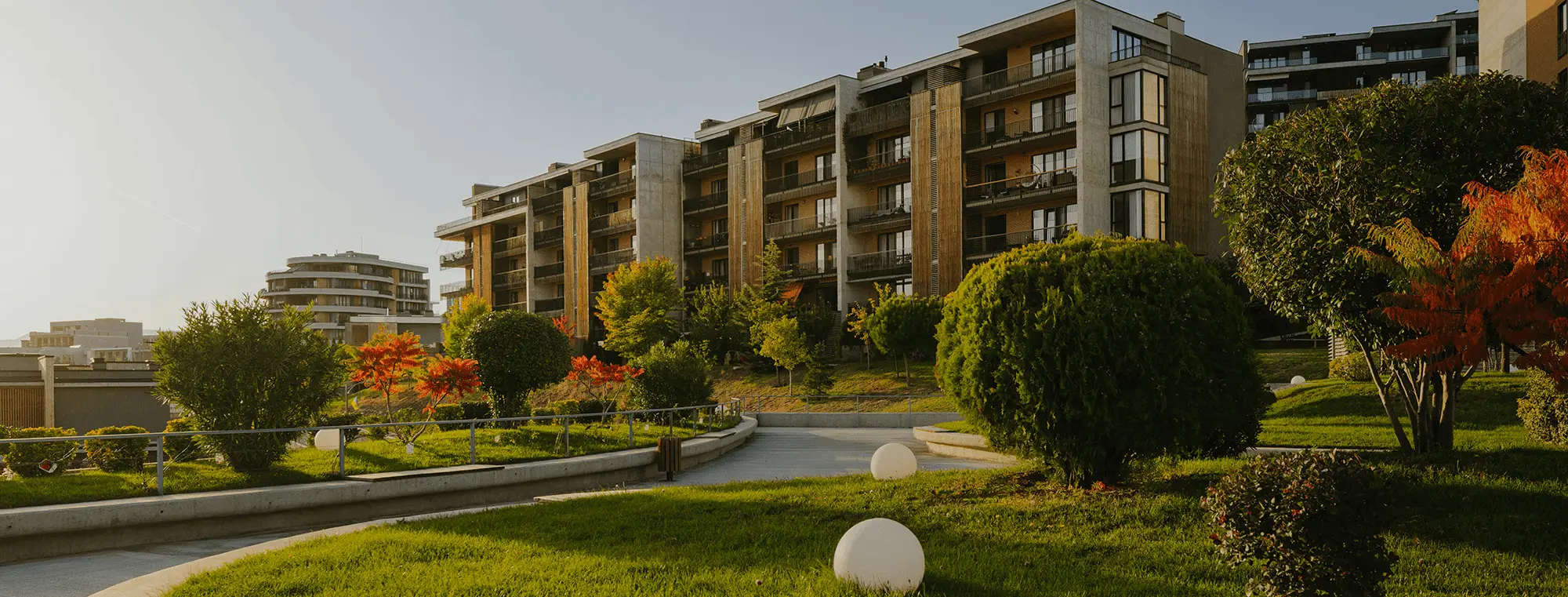 Modern residential complex surrounded by greenery and soft landscape lines