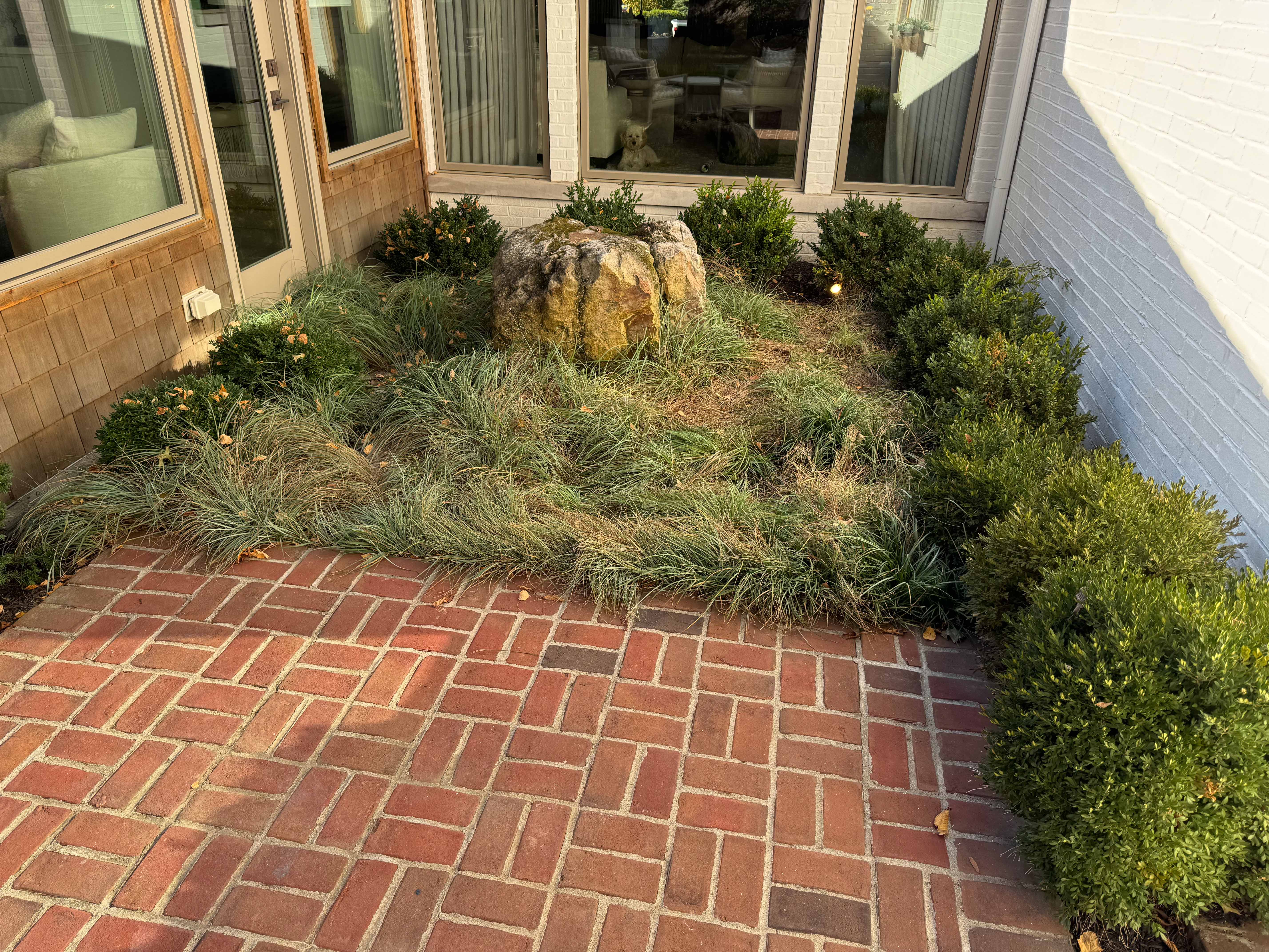 Brick patio with ornamental grass and landscape boulder