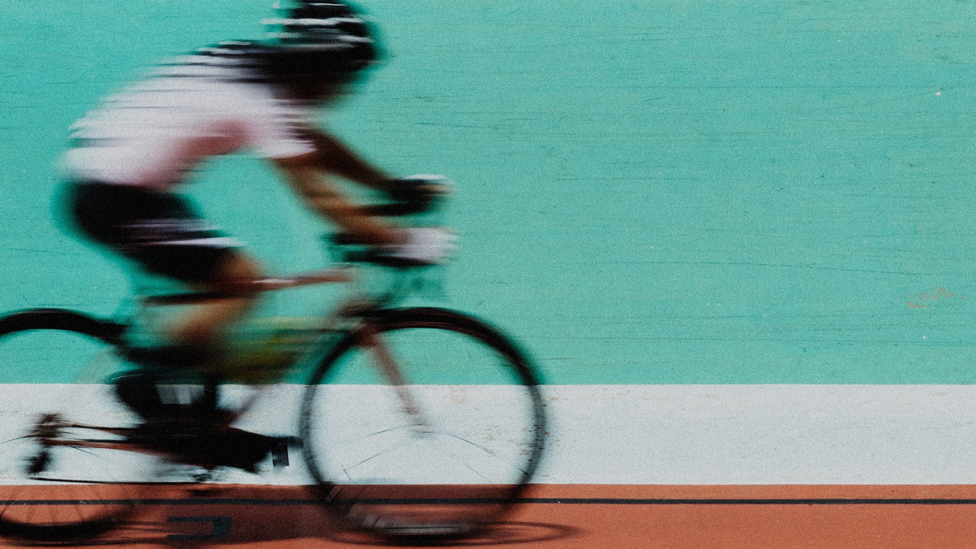 A motion blur and grainy image of a cyclist on a track.