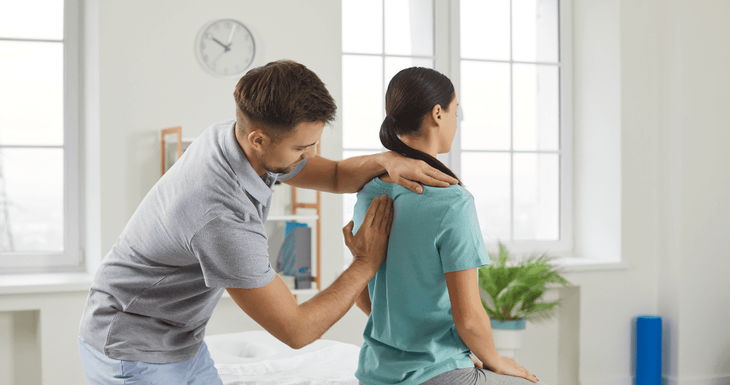 Chiropractor checking a patient's back for spinal alignment in a bright clinic.