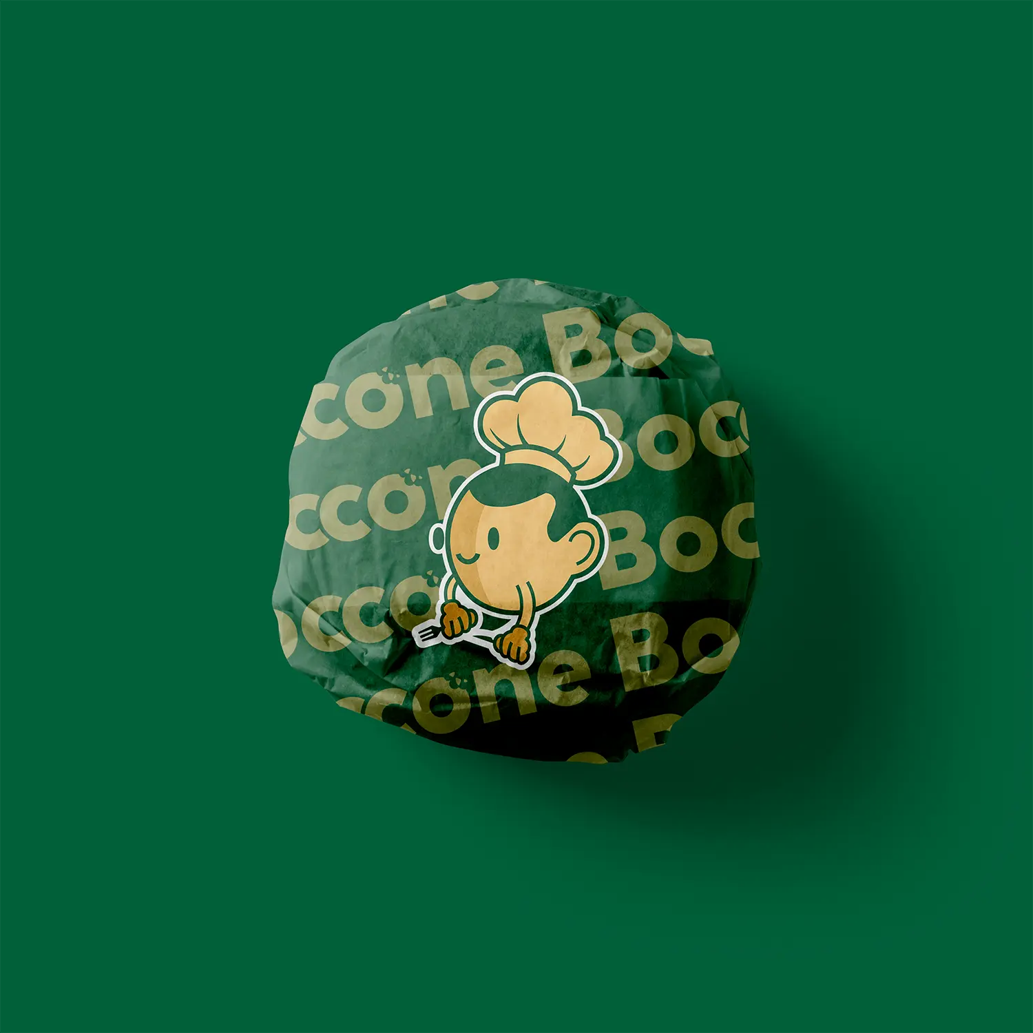 Boccone Café burger wrapped in dark green branded paper featuring the café’s mascot illustration on a matching green background
