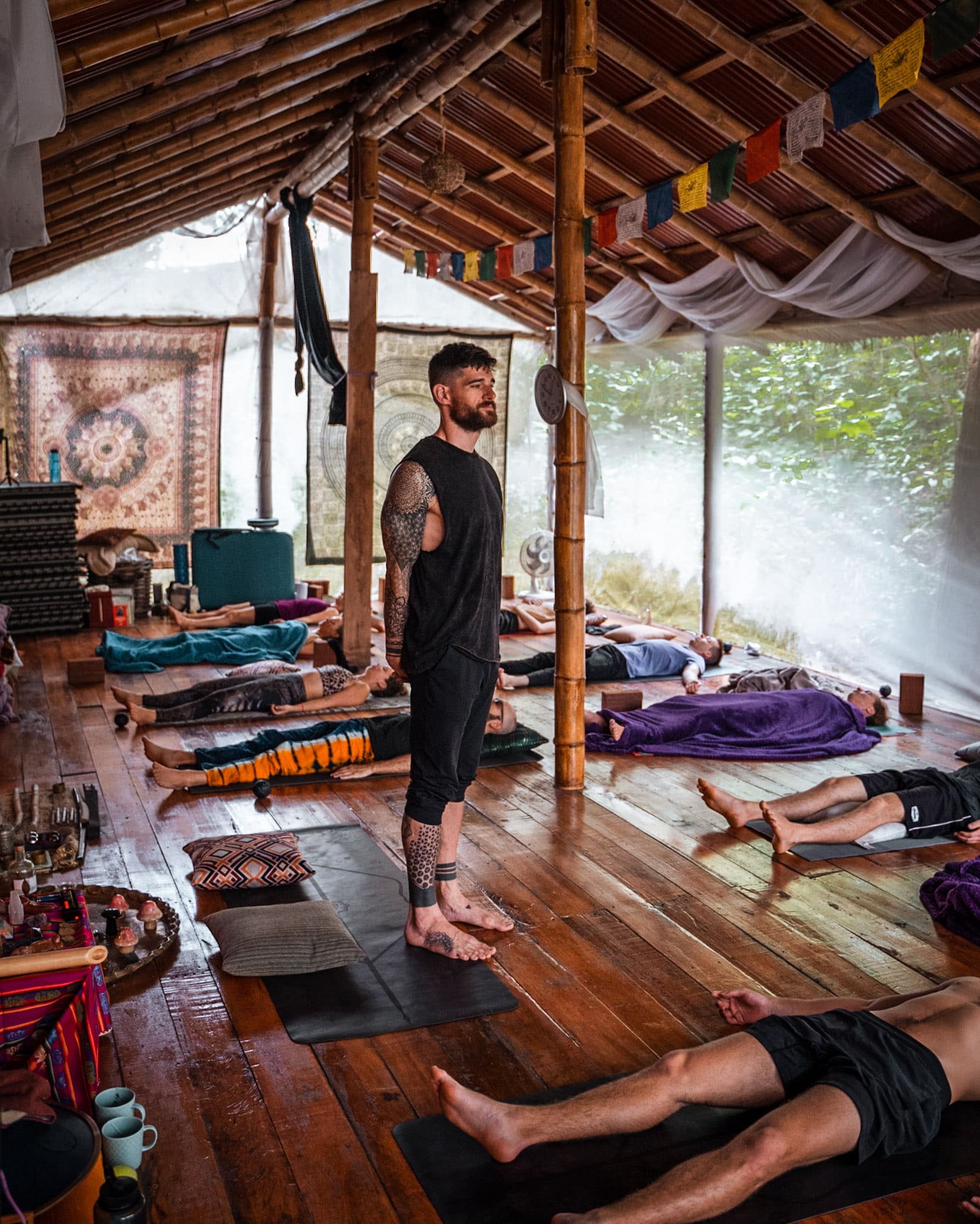 Flo stands guiding retreat guests while they rest in savasana during a yoga session.