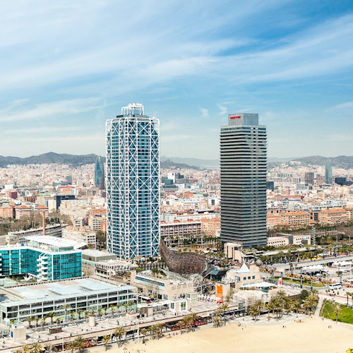 俯瞰城市景观,两座高耸的摩天大楼,周围建筑物,前景是沙滩,映衬着蓝天。