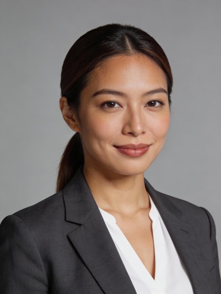 A professional woman with long dark hair in a ponytail, wearing a gray blazer and white blouse, smiles confidently against a plain backdrop.