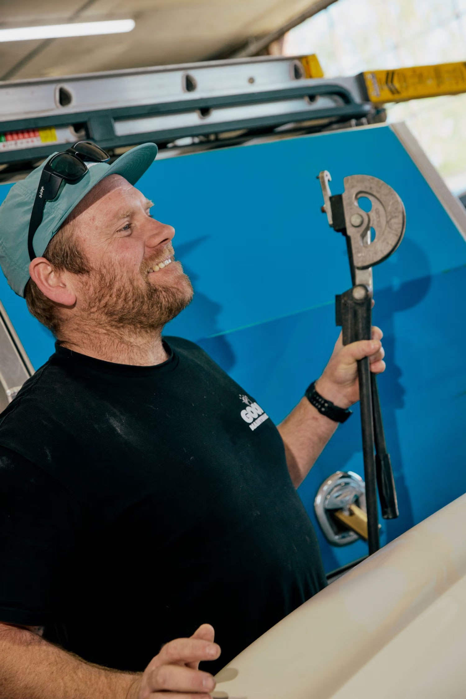 Technician smiling while holding plumbing tools beside a company vehicle.
