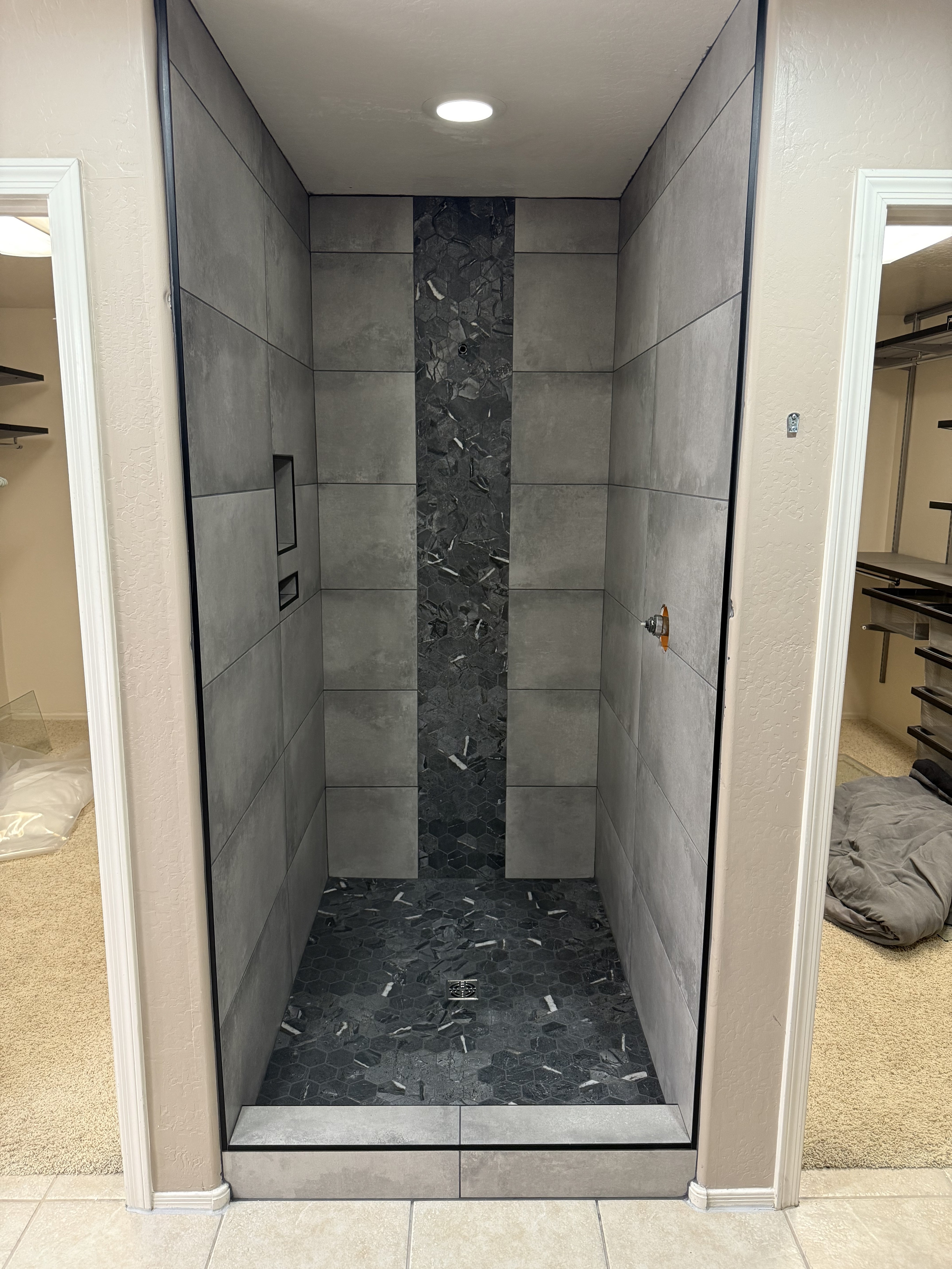 Luxurious bathroom vanity area with a dramatic wall featuring large format natural stone tiles in varying earthy tones and complex veining, serving as a striking backsplash above a double sink vanity.