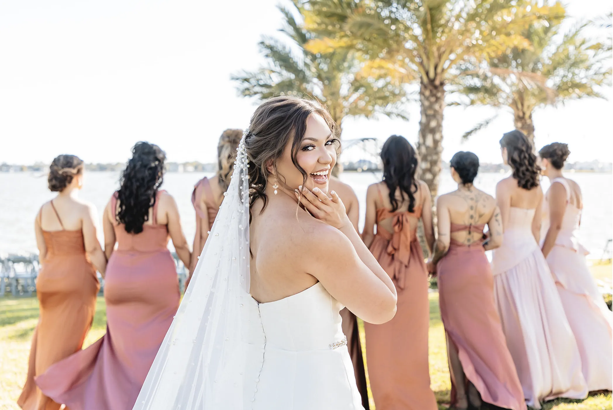 A bride and groom share a kiss surrounded by a joyful bridal party.