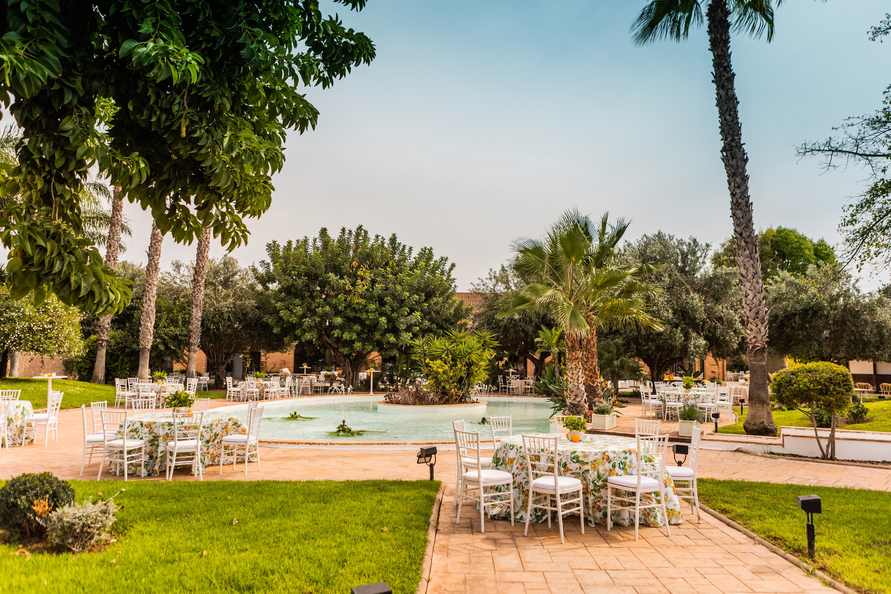 A winding road cuts through rocky terrain, surrounded by patches of green grass and illuminated by sunlight.