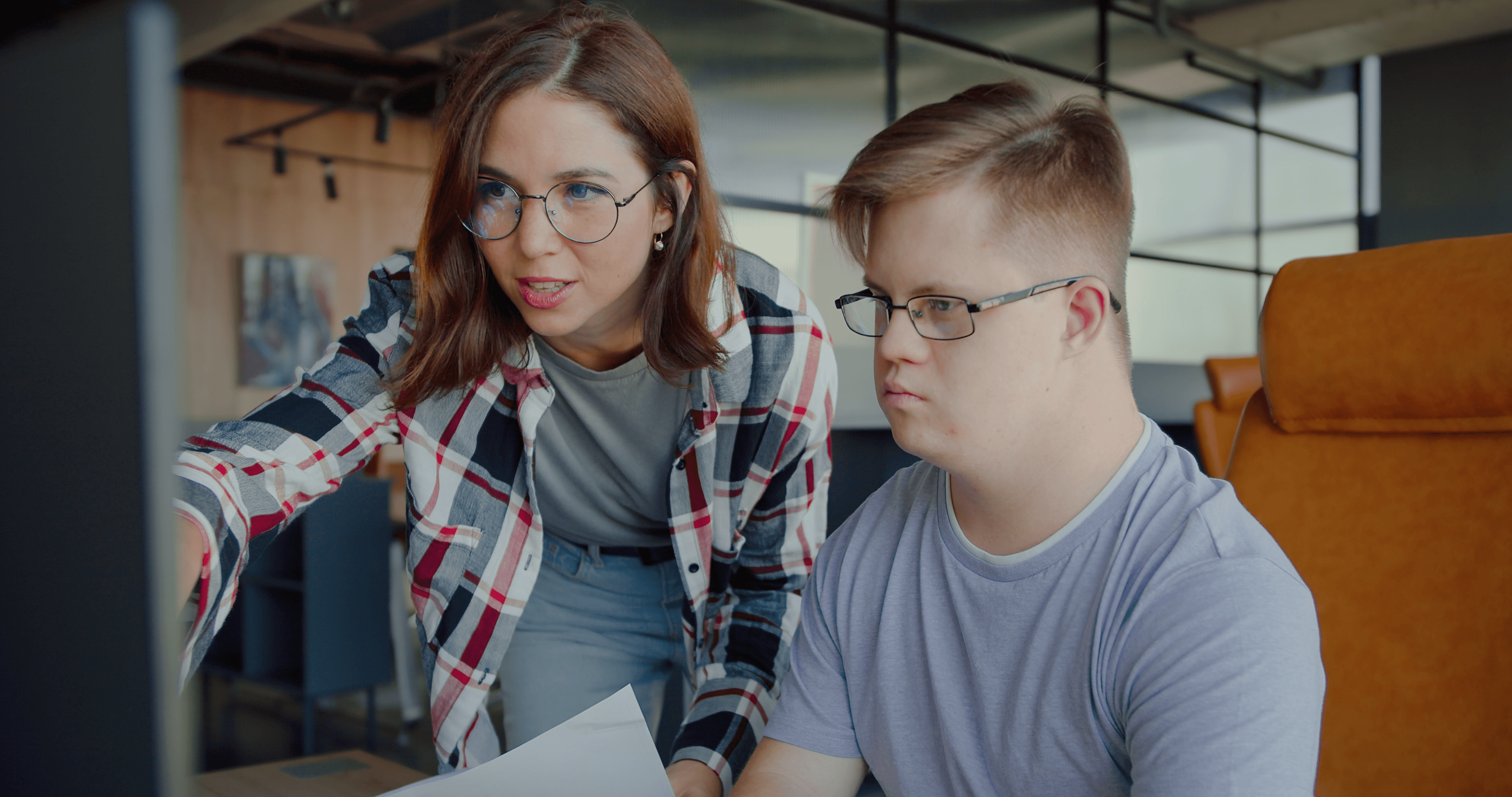 A women and a man with down syndrome on a computer.