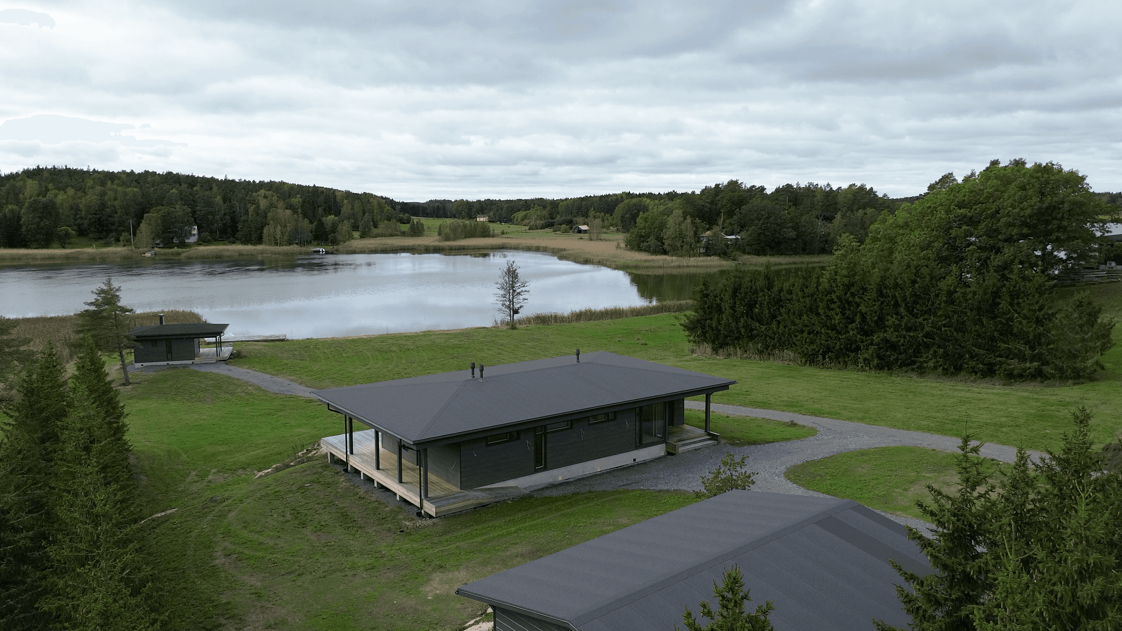 House depicted from an elevated angle, carport, sauna, and sea in the view.